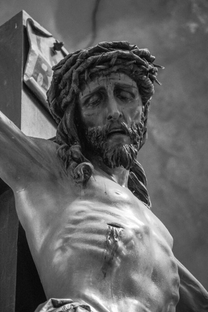 Black and white close-up of a crucifix sculpture conveying religious devotion.