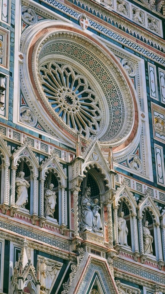 Detailed view of the gothic facade of Florence Cathedral showcasing intricate sculptures and rose window.